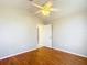 Bedroom with wood-look floors, neutral walls, ceiling fan, and doorway to hall bathroom at 2518 Foxbridge Ter, The Villages, FL 32162