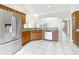 Galley kitchen featuring wood cabinetry, stainless steel appliances, and light tile floors at 2518 Foxbridge Ter, The Villages, FL 32162