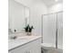 Clean and modern bathroom features a walk-in shower with glass doors, vanity with a large mirror, and white tile at 3193 Armstrong Ave, Clermont, FL 34714