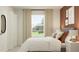 Bedroom featuring warm paint, modern decor, a gray upholstered bed, white linens, and bedside tables with a large window at 1934 Sarah St, Winter Haven, FL 33884