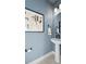 Stylish powder room featuring blue walls, modern art, and a pedestal sink with black fixtures at 15113 Grove Lake Dr, Winter Garden, FL 34787