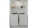 Bright laundry room with modern washer and dryer units and convenient shelving for storage solutions at 15113 Grove Lake Dr, Winter Garden, FL 34787