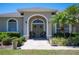 Inviting front entrance with arched doorway, olive-green door, seating and potted plants at 119 Lake Mariam Way, Winter Haven, FL 33884