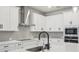 Close-up of a kitchen with modern appliances, a stylish range hood, and a matte black faucet at 6057 Sacred Oak Ave, Mount Dora, FL 32757