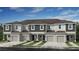 Beautiful exterior of new townhomes featuring attached garages, covered entryways and neutral-toned siding under a blue sky at 7605 Waterscape Dr, Groveland, FL 34736