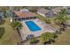 Aerial view of community pool with clubhouse, lounge chairs, palm trees, and surrounding green space at 540 Buckingham Cir, Davenport, FL 33897