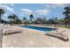 Community pool with brick paver deck, lounge chairs, and white aluminum fence in a tropical neighborhood at 540 Buckingham Cir, Davenport, FL 33897