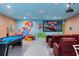 Whimsical game room with a large screen, tiered seating, and fun wall decor, perfect for entertaining at 1529 Euston Dr, Reunion, FL 34747