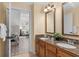 Bathroom with double sinks, granite countertops, wood cabinets, and a view to the bedroom and sitting area at 7636 Heritage Crossing Way, Reunion, FL 34747