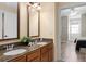 Bathroom featuring double sinks, granite countertops, wood cabinets, and an open doorway to bedroom at 7636 Heritage Crossing Way, Reunion, FL 34747