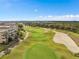 Scenic aerial of golf course with lush green fairways, sand traps, and modern residential buildings in the background at 7636 Heritage Crossing Way, Reunion, FL 34747