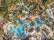 Aerial view of a luxurious resort pool featuring a lazy river, palm trees, lounge chairs, and vibrant blue umbrellas at 7636 Heritage Crossing Way, Reunion, FL 34747