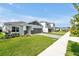 Street view of modern single-Gathering homes with gray brick accents, well-manicured lawns, and paved driveways at 5774 Greenery Ln, St Cloud, FL 34771