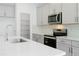 Close-up of a kitchen featuring gray cabinets, stainless steel appliances, and white countertops at 5774 Greenery Ln, St Cloud, FL 34771