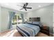 Well-lit bedroom featuring a queen-size bed, ceiling fan, and large window with decorative curtains at 754 Andalusia Loop, Davenport, FL 33837