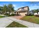 Inviting two-story home with a brick driveway, a two-car garage, and manicured lawn featuring mature shade trees at 754 Andalusia Loop, Davenport, FL 33837