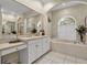 Bathroom featuring a tub, white cabinets, and a large mirror at 867 Hanover Way, Lakeland, FL 33813