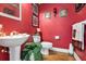 Stylish powder room with red walls, a pedestal sink, decorative accents, and hardwood floors at 867 Hanover Way, Lakeland, FL 33813