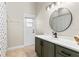 Bathroom with a single sink vanity, round mirror, and access door to outside at 1112 View Pointe Cir, Lake Wales, FL 33853