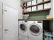 Efficient laundry room featuring a front loading washer and dryer set, wooden shelves, and a utility sink at 1112 View Pointe Cir, Lake Wales, FL 33853