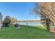 Lush backyard with mature trees, a barbecue grill, and a picturesque view of the serene lake at 10837 Versailles Blvd, Clermont, FL 34711