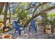 Relaxing backyard seating area with comfortable blue chairs, surrounded by lush greenery and potted plants at 3688 Hurlbut Cir, Lake Wales, FL 33898