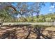 Expansive backyard featuring a white fence line, mature trees casting shadows, and ample green space for outdoor activities at 3688 Hurlbut Cir, Lake Wales, FL 33898