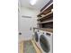 Well-lit laundry room features a modern washer and dryer, wood shelving, tile flooring, and a blue accent rug at 3688 Hurlbut Cir, Lake Wales, FL 33898