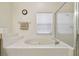 Spacious white tiled soaking tub and separate glass shower in bright bathroom at 4002 Bougainvillea Pl, Kissimmee, FL 34746
