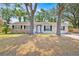 Single story home featuring black shutters, fresh paint, and mature shade trees at 2415 Sutton Rd, Lakeland, FL 33810