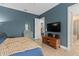 View of a bedroom with blue walls, a comfy bed, wood floors and a doorway to the bathroom at 9170 Tavistock Lakes Blvd, Orlando, FL 32827