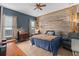 This bedroom boasts a wooden accent wall, large windows, and neutral toned decor and furnishings at 9170 Tavistock Lakes Blvd, Orlando, FL 32827