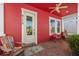 Inviting front porch with vibrant red walls, comfortable seating, and a charming brick floor at 9170 Tavistock Lakes Blvd, Orlando, FL 32827