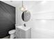 Stylish bathroom featuring a black accent wall, round mirror, and a modern vanity with sleek fixtures at 1508 Leighton Ave, Lakeland, FL 33803