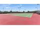 Outdoor tennis courts with green and red surface, surrounded by a black fence, and lit by tall lampposts at 5038 Barnet Dr, Davenport, FL 33837