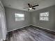 Comfortable bedroom featuring wood-look floors, two windows, and a modern ceiling fan at 1011 Old Lake Alfred Rd, Auburndale, FL 33823