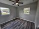 Cozy bedroom with wood-look floors, a ceiling fan, and plenty of natural light from two windows at 1011 Old Lake Alfred Rd, Auburndale, FL 33823