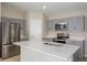 Close-up of a modern kitchen with stainless steel appliances, gray cabinets, and an island with quartz countertops at 1026 Foreshore Ln, Haines City, FL 33844