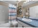 This bathroom includes a shower/tub combo, decorative shelves and a vanity with patterned countertop at 112 Thorne Meadow Pass, Davenport, FL 33897