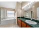 This spacious bathroom features a garden tub with window and a vanity with lots of counter space at 112 Thorne Meadow Pass, Davenport, FL 33897
