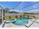This screened-in pool and spa are surrounded by a patio and landscaping at 112 Thorne Meadow Pass, Davenport, FL 33897