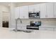 Close-up of modern kitchen with stainless steel appliances, white countertops, and undermount sink at 2047 Rosewood Cir, Lakeland, FL 33810