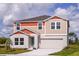 Charming two-story home featuring colorful trim, a two-car garage, and a well-manicured lawn under a sunny sky at 1554 Sage Ave, Haines City, FL 33844