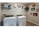 Well-lit laundry room featuring a washer and dryer, shelving, and charming dog-themed artwork for added personality at 1574 Sage Ave, Haines City, FL 33844