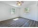 A bright bedroom with wood-look flooring has natural light from two windows and a ceiling fan at 218 W Magnolia St, Clermont, FL 34711