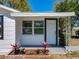 Inviting front entrance with a white door, black trim, and a small garden bed with colorful plants at 218 W Magnolia St, Clermont, FL 34711