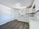 Cozy kitchen with white cabinetry, granite counters, and laminate flooring leading to the front door at 218 W Magnolia St, Clermont, FL 34711