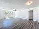 Open-concept living room with a ceiling fan and lots of natural light shining on the gray laminate floors at 218 W Magnolia St, Clermont, FL 34711