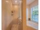 Modern bathroom featuring a bathtub and a separate glass-enclosed shower, complemented by natural light from the window at 8427 Prestbury Dr, Orlando, FL 32832