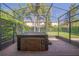Covered hot tub inside screened enclosure with brick pavers, lush landscaping, and tropical palm trees at 8427 Prestbury Dr, Orlando, FL 32832